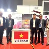 Đại diện Đoàn Hiệp hội Gỗ Bình Dương chụp ảnh lưu niệm với khách tham quan trước gian hàng của Việt Nam tại Hội chợ. (Ảnh: Ngọc Thúy/TXTVN)
