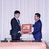 Phó Chủ tịch Ủy ban Nhân dân Thành phố Hồ Chí Minh Bùi Xuân Cường (phải) trao quà đối ngoại cho Thứ trưởng Bộ Ngoại giao Nhật Bản Komura Masahiro. (Ảnh: Xuân Khu/TTXVN)