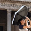 Du khách che ô khi di chuyển trong nắng gắt tại Rome, Italy ngày 18/7/2023. (Ảnh: THX/TTXVN)