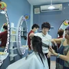 Chị Đào, chủ salon đang tự tay làm tóc cho một khách hàng tên Thu. (Ảnh: PV/Vietnam+)
