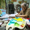 Có một người họa sĩ già ngày ngày vẫn cặm cụi vẽ tranh và làm một cái ‘nghề’ không ai coi là nghề: vẽ báo tường. (Ảnh: Minh Sơn/Vietnam+)