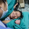 Khoảnh khắc hạnh phúc tột cùng của chị Nguyễn Thị Mỹ Hạnh khi ngắm nhìn đứa con trai mới chào đời mạnh khỏe. (Ảnh: Minh Sơn/Vietnam+)