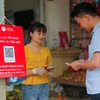 Người dân có thể dễ dàng thanh toán một bó rau hoặc một túi hoa quả chỉ bằng việc quét mã QR hoặc chuyển tiền qua số điện thoại. (Ảnh: Minh Sơn/Vietnam+)