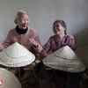 Những hình ảnh ấn tượng các bà, các chị, đang ngồi khâu nón lá, miệng cười nói vui vẻ khiến du khách rất thích thú. (Báo ảnh Việt Nam/Vietnam+)