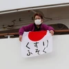 Một hành khách người Nhật Bản giơ quốc kỳ in dòng chữ "Thiếu thuốc men." (Ảnh: Reuters)