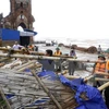Cán bộ đồn Biên phòng Văn Lý giúp người dân khắc phục sau bão số 1 đi qua tại khu vực bãi biển xã Hải Lý (Hải Hậu). (Ảnh: Minh Quyết/TTXVN)