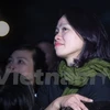 Chị Mai Hoa, vợ Trần Lập đứng thu mình ở một góc nhỏ phía khán giả lắng nghe những bài hát của anh. (Ảnh: Minh Sơn/Vietnam+)