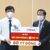 Ông Phạm Quốc Thanh (bên phải) - Tổng Giám đốc HDBank trao ủng hộ cho ông Nguyễn Thanh Long - Bộ trưởng Bộ Y tế. (Ảnh: Vietnam+)