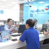 Cán bộ VietinBank hướng dẫn khách hàng xác thực sinh trắc học. (Ảnh: Vietnam+)