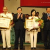Chủ tịch nước và Bí thư Thành ủy trao tặng danh hiệu anh hùng cho Đại tá Lê Văn Nón và Thượng tá Phan Thị Ngọc Tươi. (Ảnh: Hoàng Hải/TTXVN)