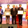 Ông Soucan Mahalath, Bí thư Trung ương Đảng Nhân dân Cách mạng Lào, Bí thư Thành ủy kiêm Đô trưởng Vientiane trao Huân chương cho đại diện thành niên Hà Nội và TP.HCM. (Ảnh: Hoàng Chương/Vietnam+)