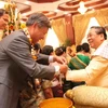 Đại sứ Nguyễn Mạnh Hùng đã buộc chỉ cổ tay chúc phúc cho Tổng Bí thư, Chủ tịch nước Lào Chummaly Saynhasone. (Ảnh: Hoàng Chương/Vietnam+)