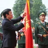 Chủ tịch nước gắn Huân chương Quân công hạng Nhất lên Cờ truyền thống của Học viện Biên phòng. (Ảnh: Nguyễn Khang/TTXVN)