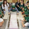 Các em học sinh và phụ huynh đang hoàn thành nốt phong kẹo. (Nguồn: Kyodo) 