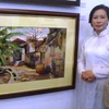 Họa sỹ Bảo Hiền bên một bức tranh của mình (Ảnh: Phương Mai/Vietnam+)