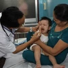 Khám chữa bệnh cho trẻ bị tay, chân, miệng. (Ảnh: Phương Vy/TTXVN)