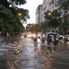 Mưa lớn ngập phố, khiến người tham gia giao thông gặp rất nhiều khó khăn. (Ảnh: Hùng Võ/Vietnam+)
