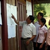 Đồng bào dân tộc Hà Nhì, Mường Nhé, tìm hiểu tiểu sử các ứng cử viên tại địa điểm bỏ phiếu. (Ảnh: Trọng Đức/TTXVN)