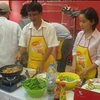 Hai nhà báo Lê Tuấn (báo Công an Thành phố Hồ Chí Minh) và Linh Đoan (báo Tuổi Trẻ) đang trổ tài làm món thịt rang tôm. (Ảnh: M.H)