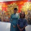 Họa sỹ Lương Khánh Toàn đứng bên một bức tranh sơn mài trưng bày tại triển lãm. (Ảnh: Ngọc Tiến/Vietnam+)