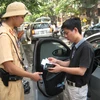 Cảnh sát giao thông xử phạt vi phạm trật tự giao thông trong ngày đầu thực hiện Nghị định 34 của Chính phủ. (Ảnh: Mạnh Hùng/Vietnam+)