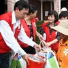 Các tình nguyện viên Hội Chữ Thập đỏ trao hàng cứu trợ cho người dân vùng lũ lụt. (Ảnh: Hồ Cầu/TTXVN)