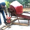 Anh Nguyễn Quốc Bảo vận hành chiếc máy tuốt lúa cải tiến do mình chế tạo. (Nguồn: baothainguyen.org.vn)