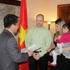 Đại sứ Việt Nam tại Canada Lê Sỹ Vương Hà trao quyết định, cùng giấy tờ về việc nhận con nuôi cho một trong hai gia đình được nhận con nuôi Việt Nam. (Ảnh: Thanh Hải/Vietnam+) 