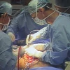 Phó Giáo sư McKay McKinnon (phải) trực tiếp phẫu thuật cắt bỏ khối u cho anh Hải. (Ảnh: Phương Vy/TTXVN)