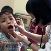 Một bệnh nhi ở xã Ba Điền, huyện miền núi Ba Tơ mắc "bệnh lạ" đang được các bác sỹ khám tại Bệnh viện đa khoa Quảng Ngãi. (Nguồn: Vnexpress)