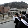 Một nhóm người dân Nhật tổ chức tượng niệm các nạn nhân thảm họa kép trước một khu vực bị động đất-sóng thần tàn phá ở tỉnh Miyagi. (Nguồn: Getty)