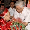 Tổng Bí thư Nguyễn Phú Trọng thăm hỏi, tặng hoa chúc mừng nhà văn Học Phi. (Ảnh: Trí Dũng/TTXVN)