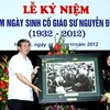 Trưởng ban Tuyên giáo Trung ương, Đinh Thế Huynh trao tặng bức ảnh có cố giáo sư Nguyễn Đình Tứ cho gia đình cố giáo sư. (Ảnh: Quý Trung/TTXVN)