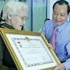 Bí thư Thành ủy Thành phố Hồ Chí Minh Lê Thanh Hải trao bằng phong tặng danh hiệu "Bà mẹ Việt Nam anh hùng" cho một mẹ liệt sỹ của thành phố. (Nguồn: TTXVN)