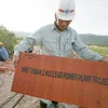 Một nhân viên nhà thầu JAPC giơ tấm biển Dự án Nhà máy điện hạt nhân Ninh Thuận 2 tại điểm khoan thăm dò, khảo sát thực địa dự án. (Ảnh: Ngọc Hà/TTXVN)