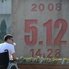 Một thanh niên bị mất cả hai chân trong trận động đất ở Tứ Xuyên đặt hoa tại đài tưởng niệm. (Nguồn: THX/TTXVN)
