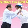 Phó Thủ tướng Nguyễn Xuân Phúc đội mũ bảo hiểm cho đại diện cán bộ, công nhân viên Tổng Công ty May 10. (Ảnh: Doãn Tấn/TTXVN)