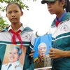Các em học sinh Trường THCS Lộc Thủy cầm bức hình Đại tướng tỏ lòng nhớ thương vô hạn với Đại tướng Võ Nguyên Giáp. (Ảnh: Thọ Thành/Vietnam+)