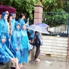 Dù trời mưa to, nhiều phụ huynh "bám trụ" tại cổng trường đợi các sĩ tử. (Ảnh PV/Vietnam+) 