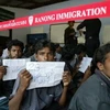 Những người Rohingya ngồi trước đồn cảnh sát trước khi bị đưa đến trung tâm tị nạn. (Nguồn: AFP)