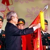 Chủ tịch Quốc hội Nguyễn Phú Trọng gắn Huân chương Sao Vàng lên Cờ truyền thống của Quân khu 3. (Ảnh: Nguyễn Dân/TTXVN)