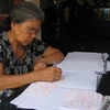 Bà Nguyễn Thị Khoát, một giáo dân đang miệt mài viết những tấm thẻ cử tri. (Ảnh: Thùy Giang/Vietnam+)