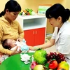 Nhân viên y tế cung cấp dịch vụ dinh dưỡng cho trẻ em. (Ảnh: TTXVN)