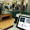 Nhân viên tại sân bay Quốc tế Nội Bài theo dõi thân nhiệt hành khách. (Ảnh: TTXVN)