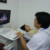 Bác sỹ siêu âm phát hiện ung thư vú cho bệnh nhân. (Ảnh: PV/Vietnam+)