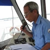 Thuyền trưởng Nguyễn Văn Bê nhắc nhở hành khách xuống phà. (Ảnh: Khánh Linh/Vietnam+)