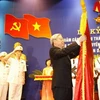 Chủ tịch Quốc hội Nguyễn Phú Trọng gắn Huân chương Sao Vàng lên lá cờ truyền thống của Công an thành phố Hà Nội. (Ảnh : Trí Dũng/TTXVN)