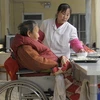 Nữ y tá chăm sóc một cụ già trên xe lăn tại nhà điều dưỡng ở Bắc Kinh ngày 8/1. (Nguồn: AFP/TTXVN)