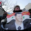 Người dân Nga mang theo chân dung Tổng thống al-Assad, bày tỏ sự ủng hộ đối với chính quyền Syria. (Nguồn: AFP/TTXVN)