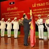 Gắn Huân chương Tự do Hạng nhất của Nhà nước Lào lên lá cờ truyền thống của Bộ Tư lệnh Cảnh vệ. (Ảnh: Doãn Tấn/Vietnam+)